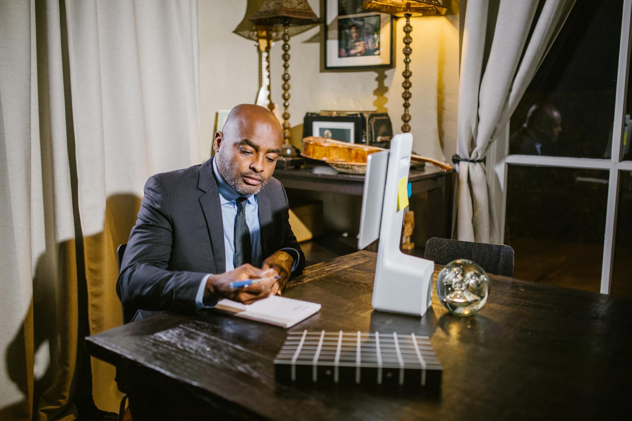 Professional businessman taking notes in a home office environment during the evening.